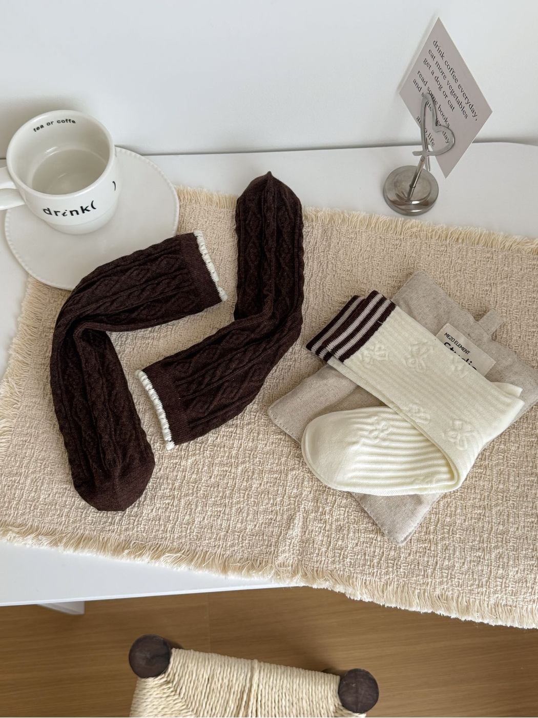 Brown cable-textured and ivory striped-cuff socks arranged on a tabletop