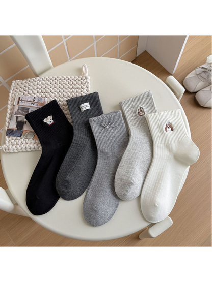 White, gray and black crew socks with assorted small motifs displayed together