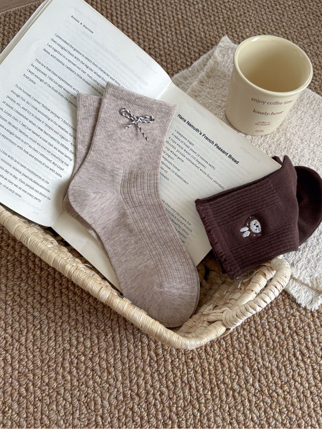 Beige bow and Dark Brown rabbit-face socks arranged in a woven tray