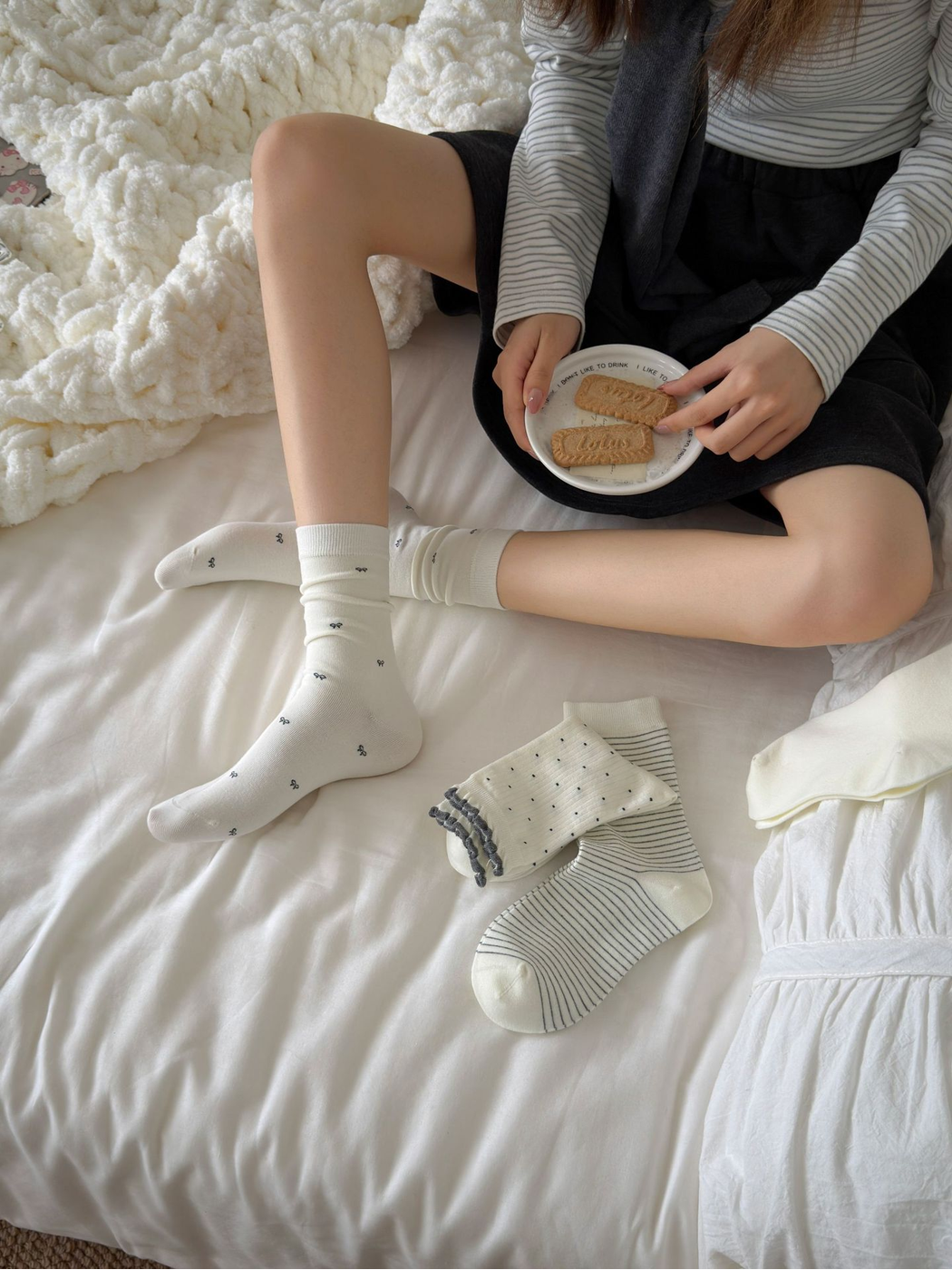 Ivory Tiny Bows crew socks worn in a relaxed seated bedroom setting