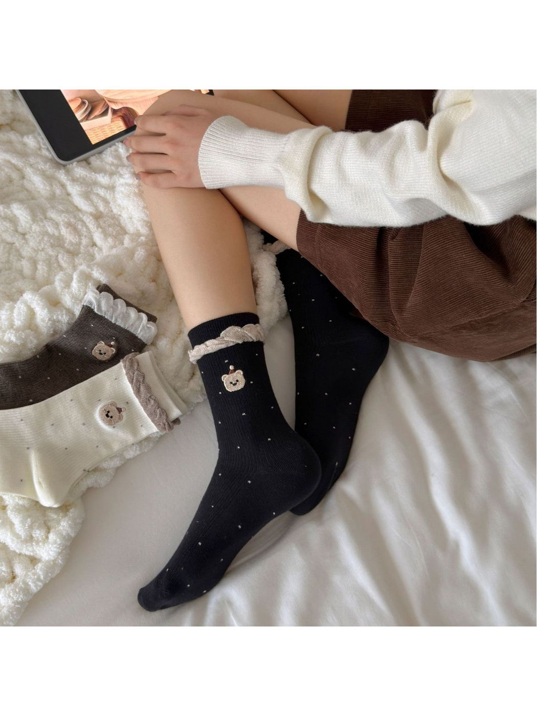 Black bear-motif crew socks worn while reclining on a bed