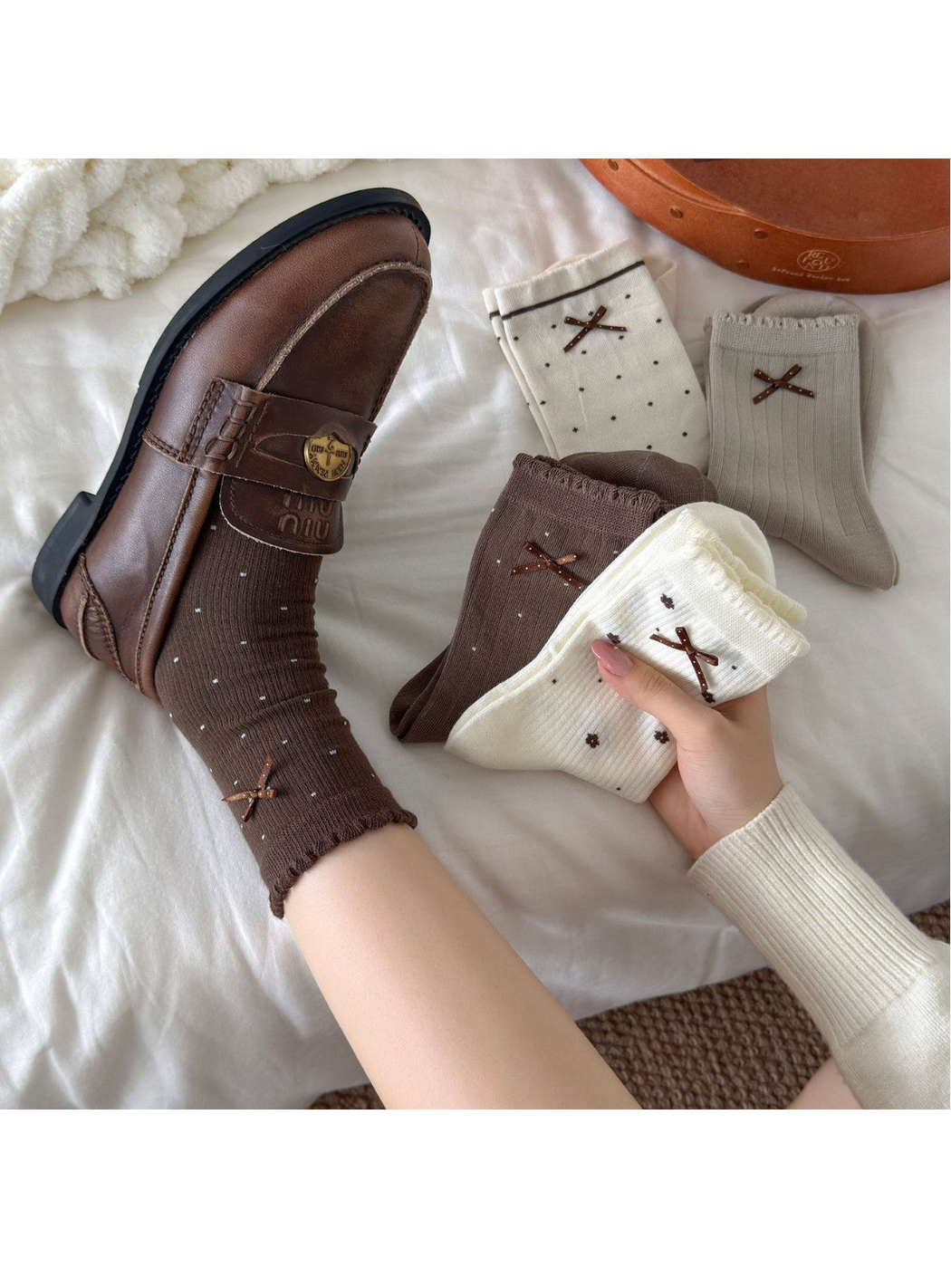 Assorted neutral crew socks with bow accents styled with brown loafers