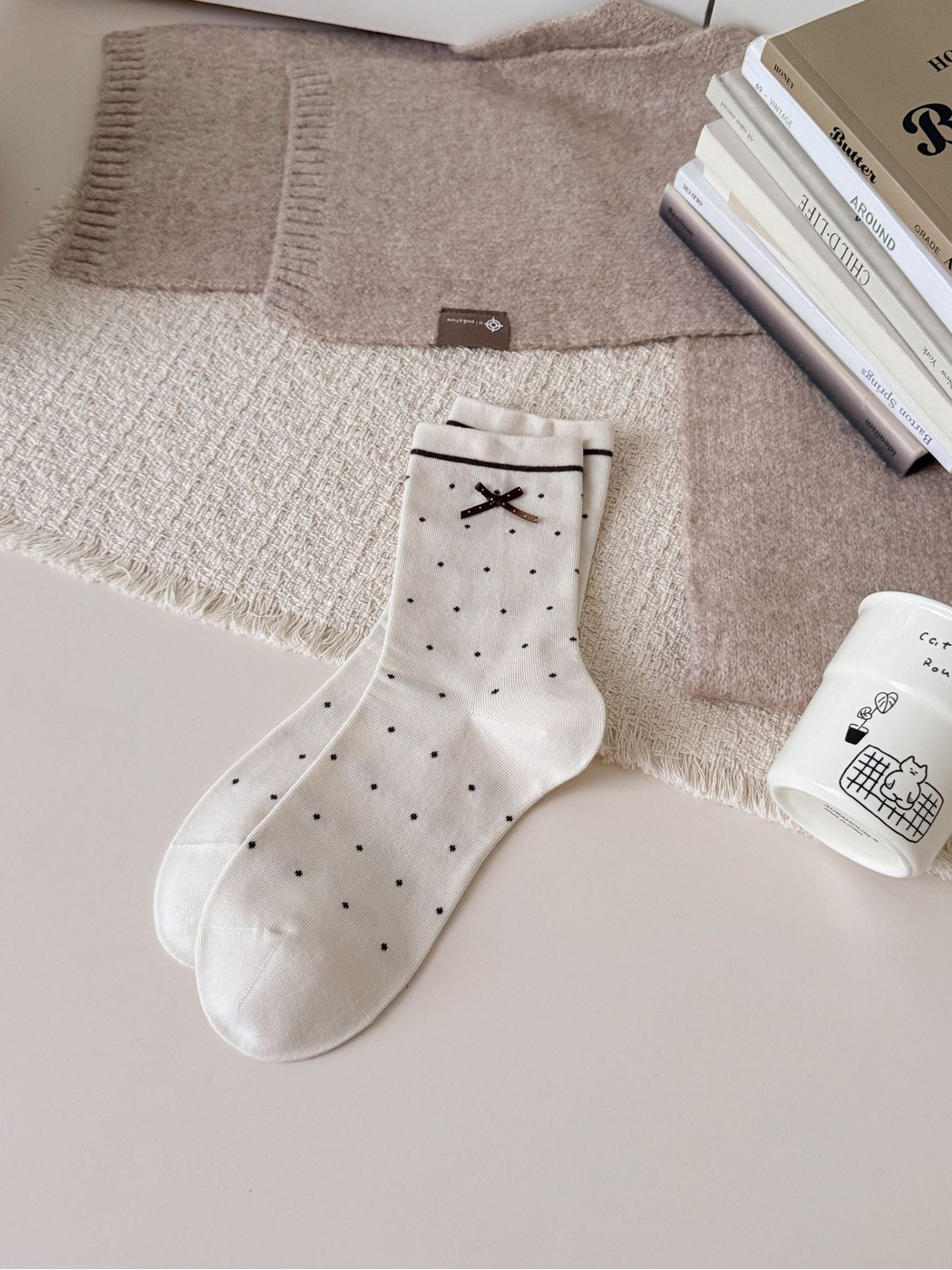 Beige crew socks with dark polka dots, striped cuffs and bow accents