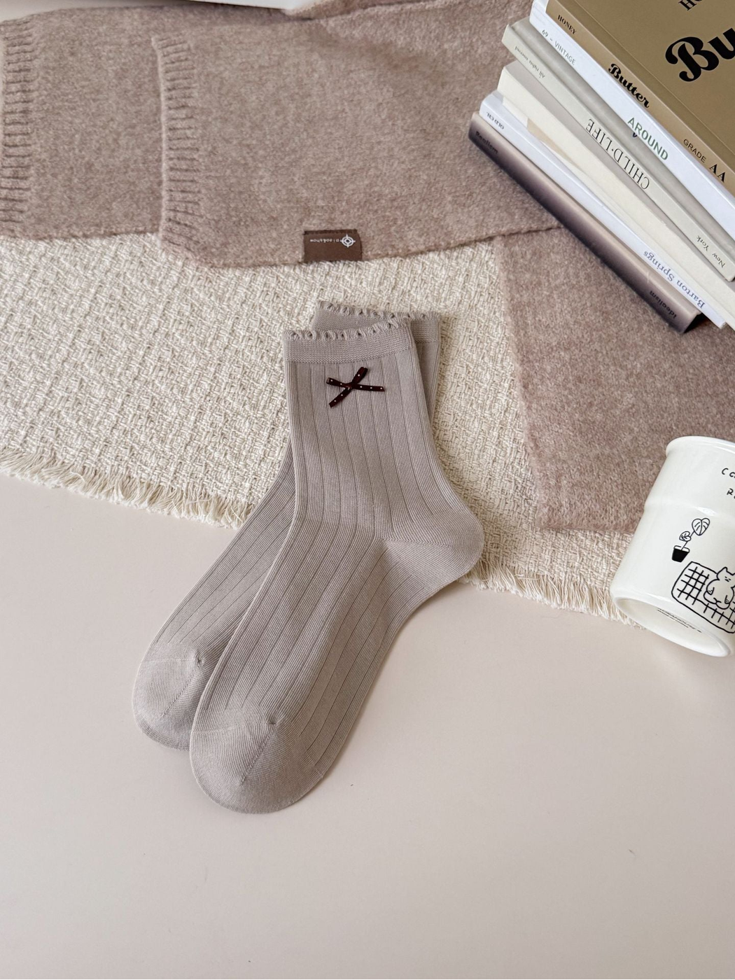Greige ribbed crew socks with ruffled cuffs and brown bow accents