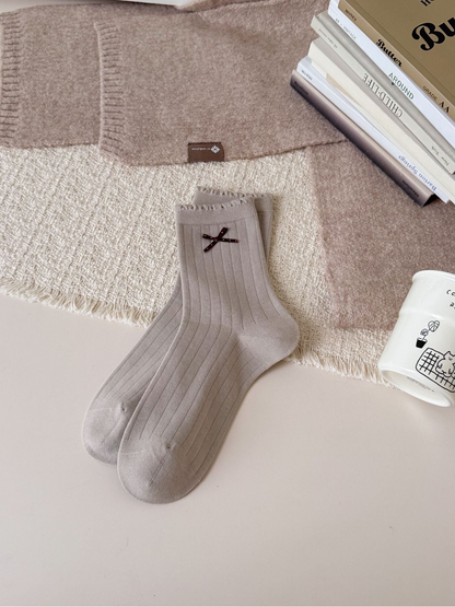 Greige ribbed crew socks with ruffled cuffs and brown bow accents