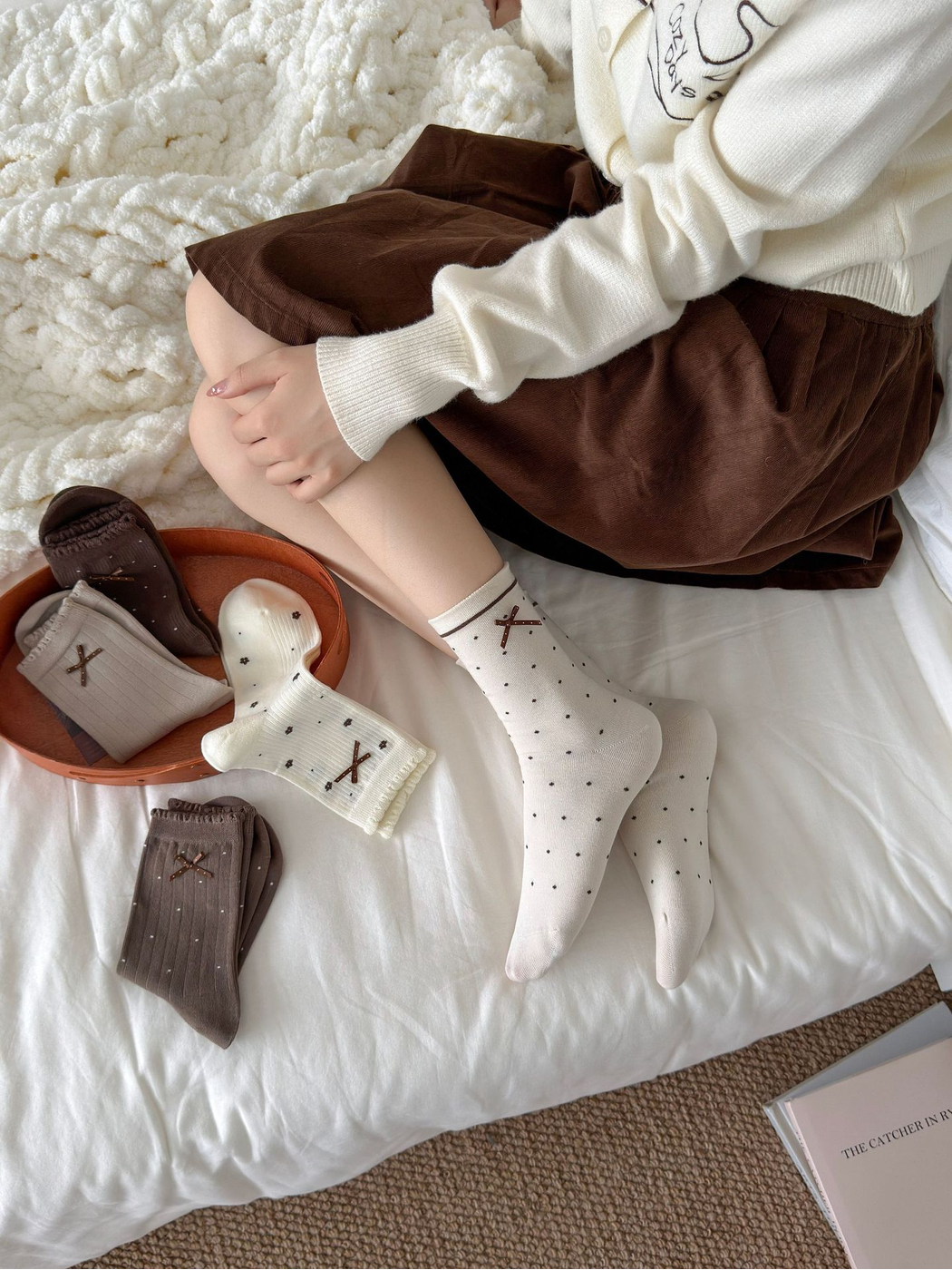 Beige polka-dot crew socks worn in a bedroom with other neutral styles nearby