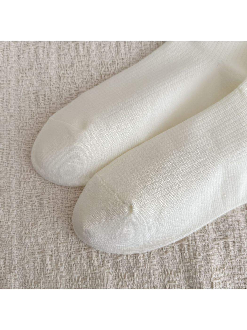 Close-up of the rounded toes and smooth knit surface on ivory socks