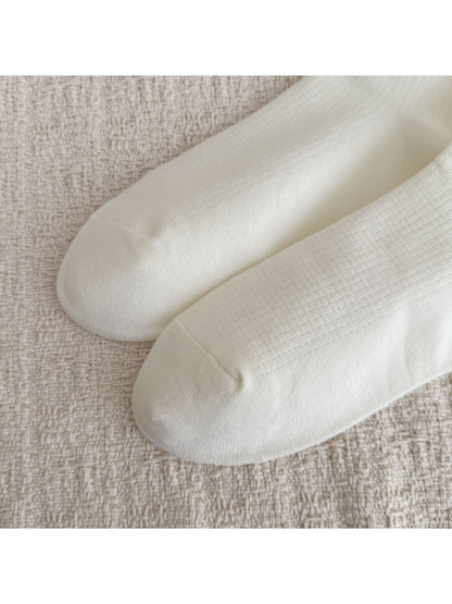 Close-up of the rounded toes and smooth knit surface on ivory socks