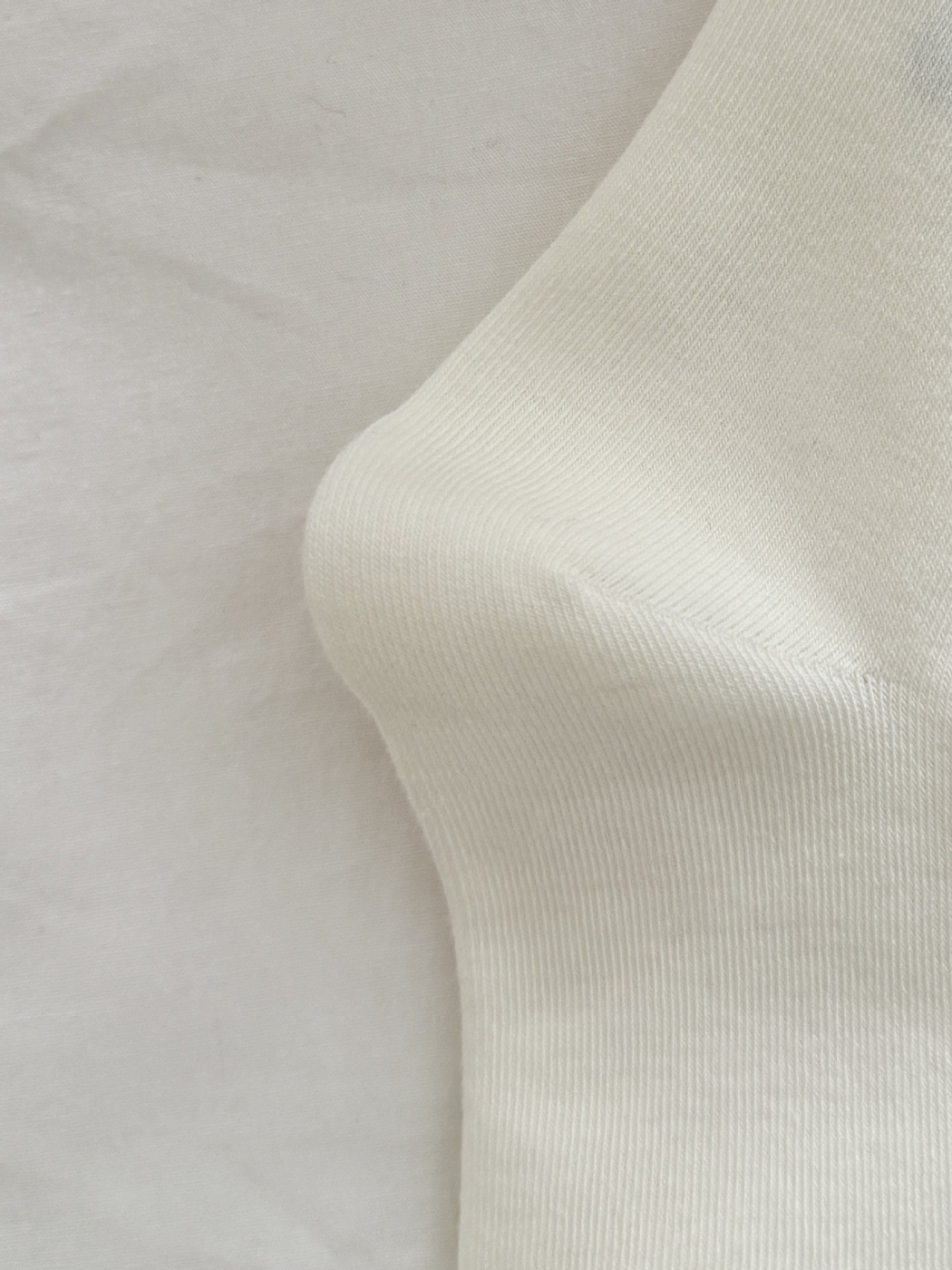 Close-up of the fine knit texture and shaped heel of an ivory crew sock