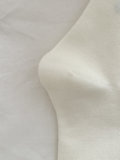 Close-up of the fine knit texture and shaped heel of an ivory crew sock