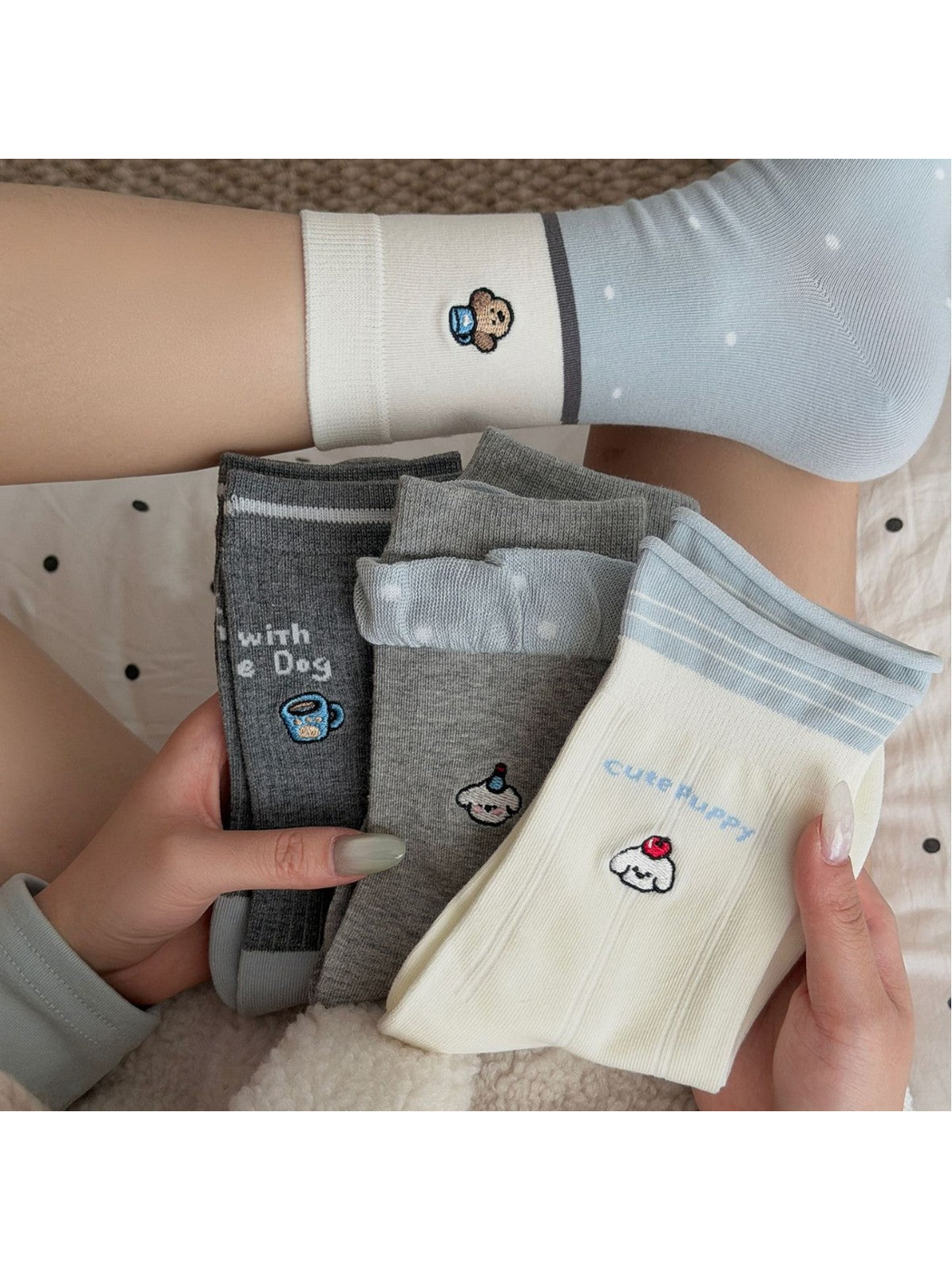 Multiple crew sock styles displayed by hand with the Bear Dots style worn