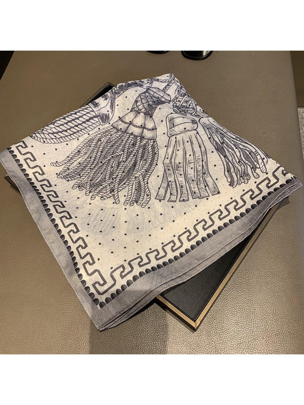Folded ivory and navy scarf showing tassel illustrations and geometric border