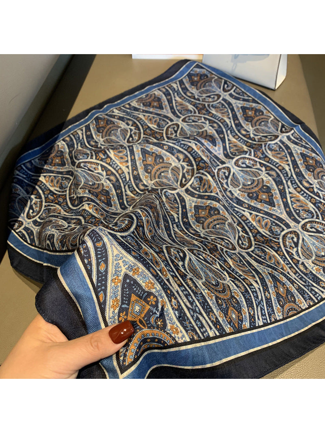 Close-up of the navy paisley scarf pattern, striped border and draped texture