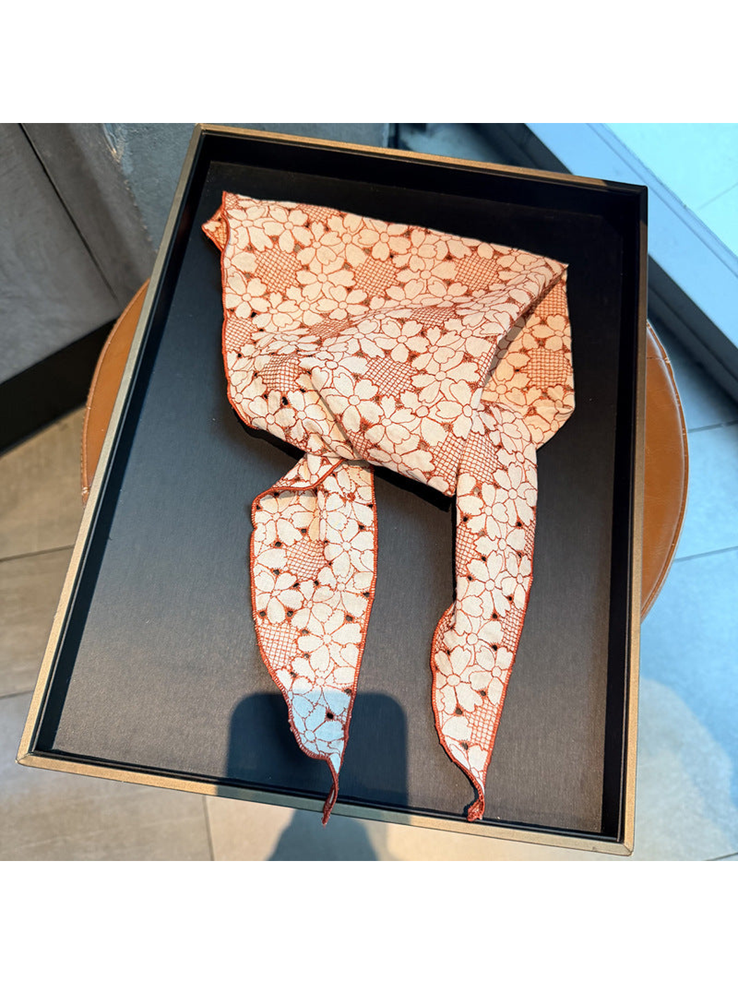 Orange Red floral openwork triangle scarf displayed on a black tray