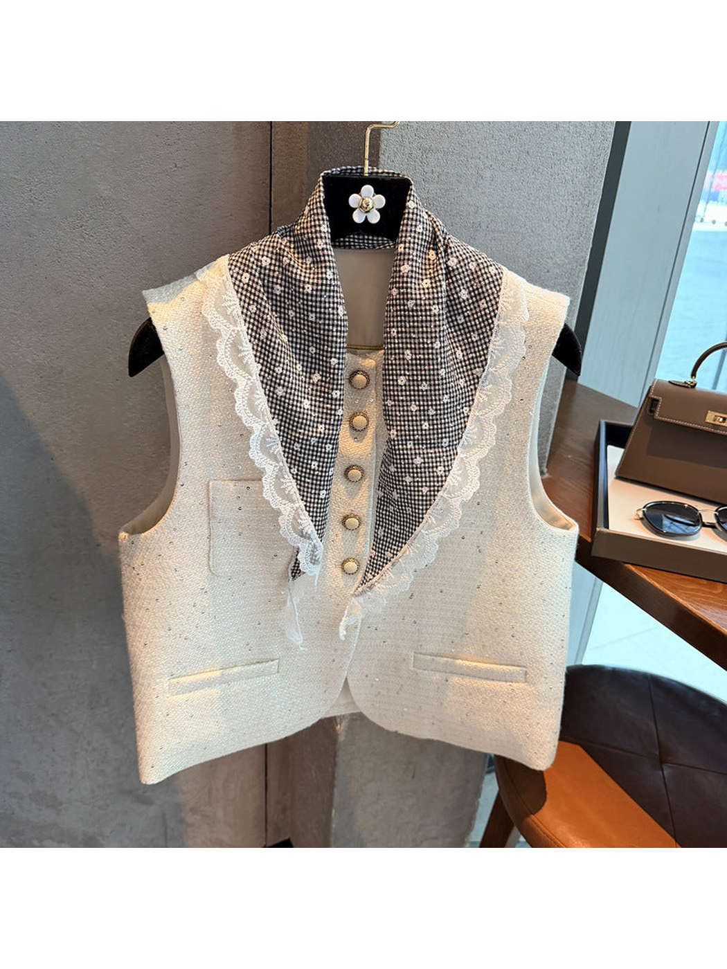 Black gingham triangle scarf draped over a cream vest to show its floral pattern and lace edging