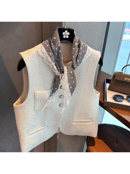 Black gingham triangle scarf tied at the neck over a cream vest