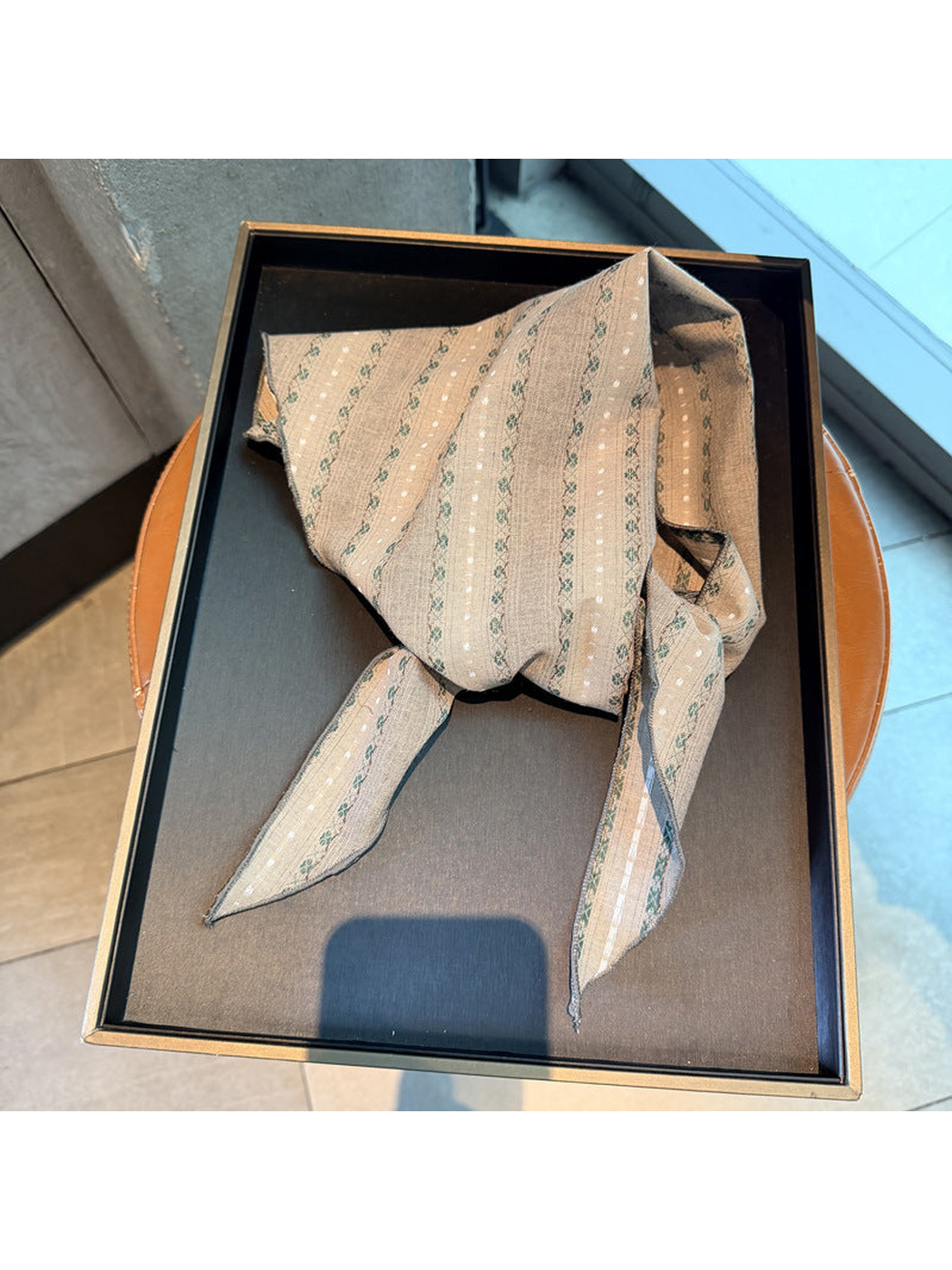 Gray striped scarf tied on a display tray