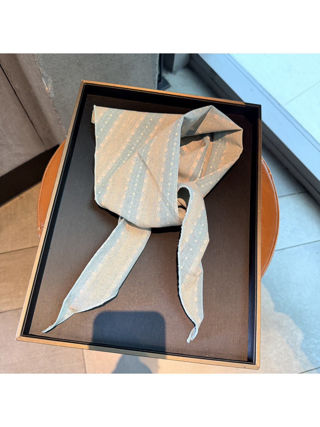 Light Blue striped scarf tied on a display tray