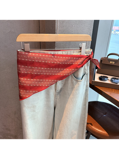 Red striped scarf tied around the waist of light-wash jeans
