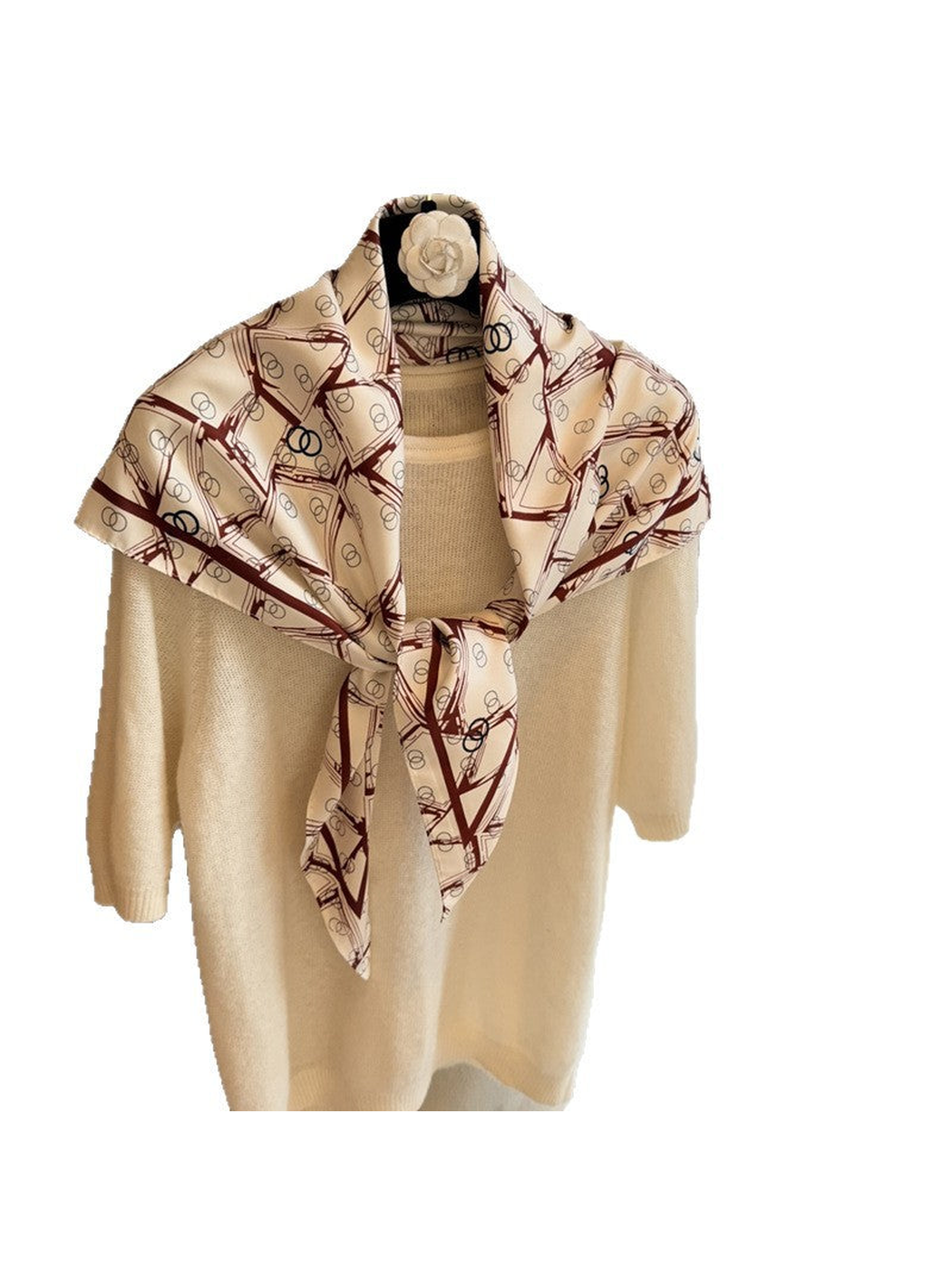 Cream triangle scarf with burgundy geometric print tied over a cream sweater