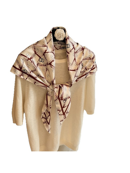 Cream triangle scarf with burgundy geometric print tied over a cream sweater