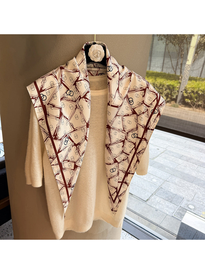 Cream triangle scarf with burgundy geometric print draped over a cream sweater