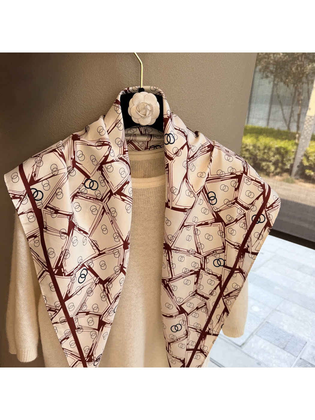 Close-up of the cream triangle scarf with burgundy geometric print and pointed ends