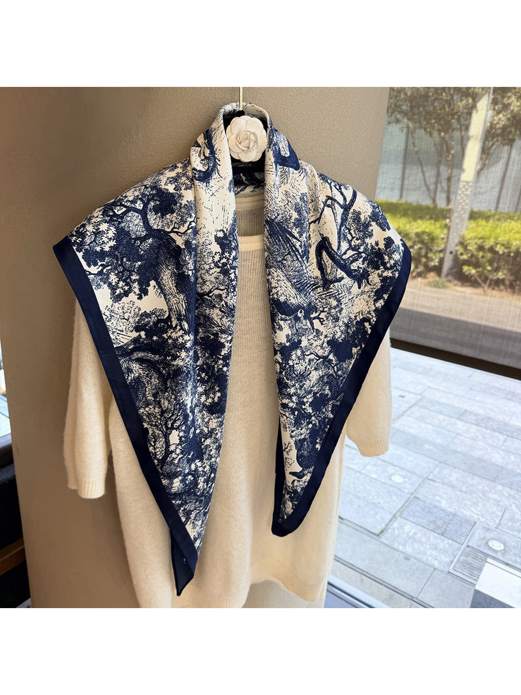 Navy and ivory triangle scarf draped over a cream sweater