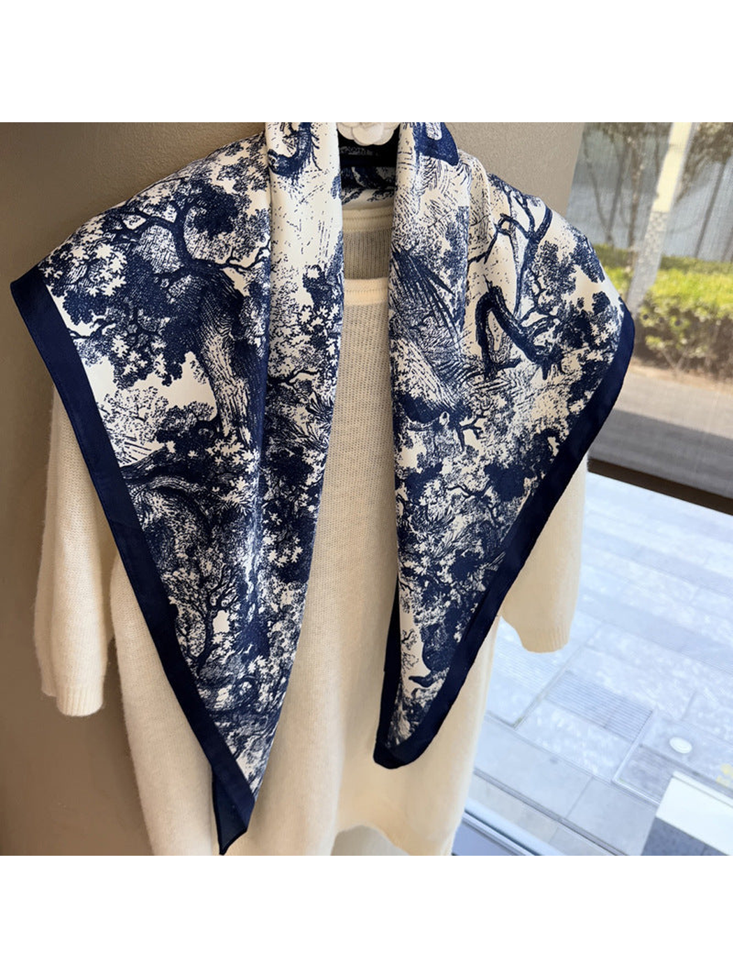 Detailed view of the navy woodland landscape print on the ivory scarf