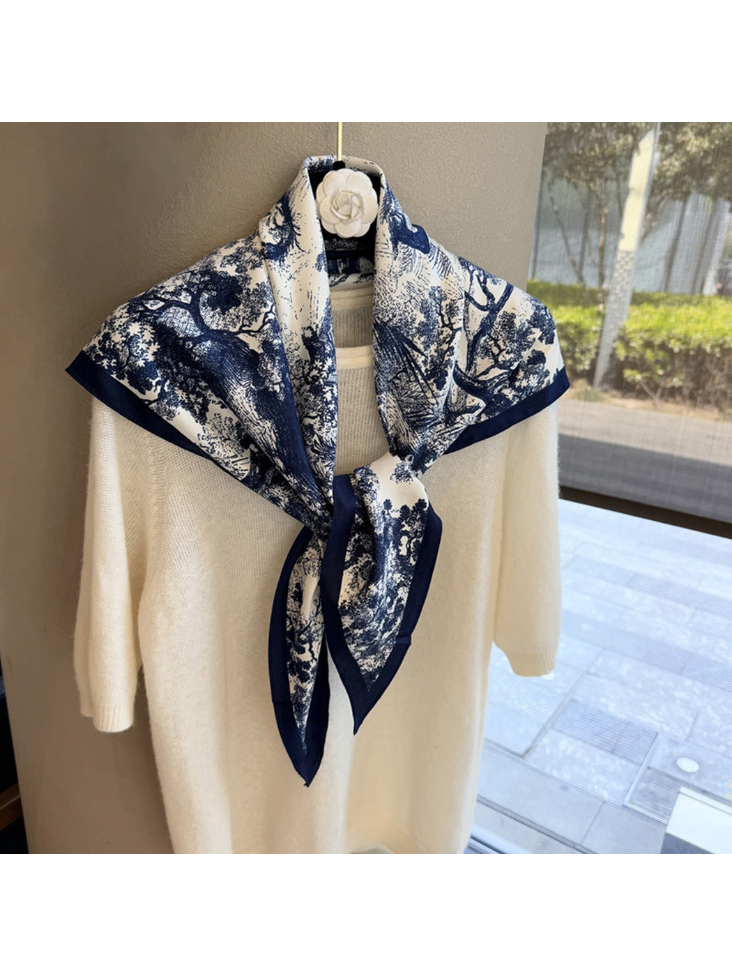 Navy and ivory triangle scarf tied over a cream sweater