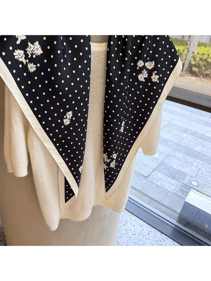 Close-up of the ivory polka dots, small floral clusters and contrasting border on the black scarf
