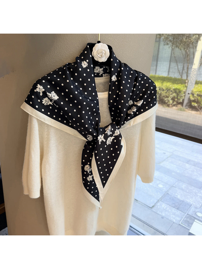 Black and ivory patterned triangle scarf styled in a front knot over a cream sweater