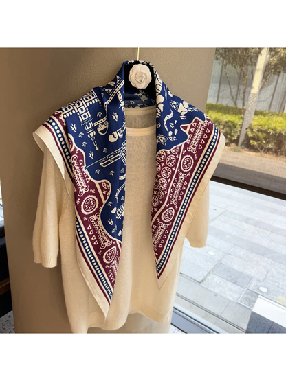 Navy, burgundy and ivory patterned scarf draped over a cream top