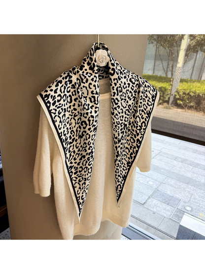Ivory and black leopard-print triangle scarf draped over a cream sweater