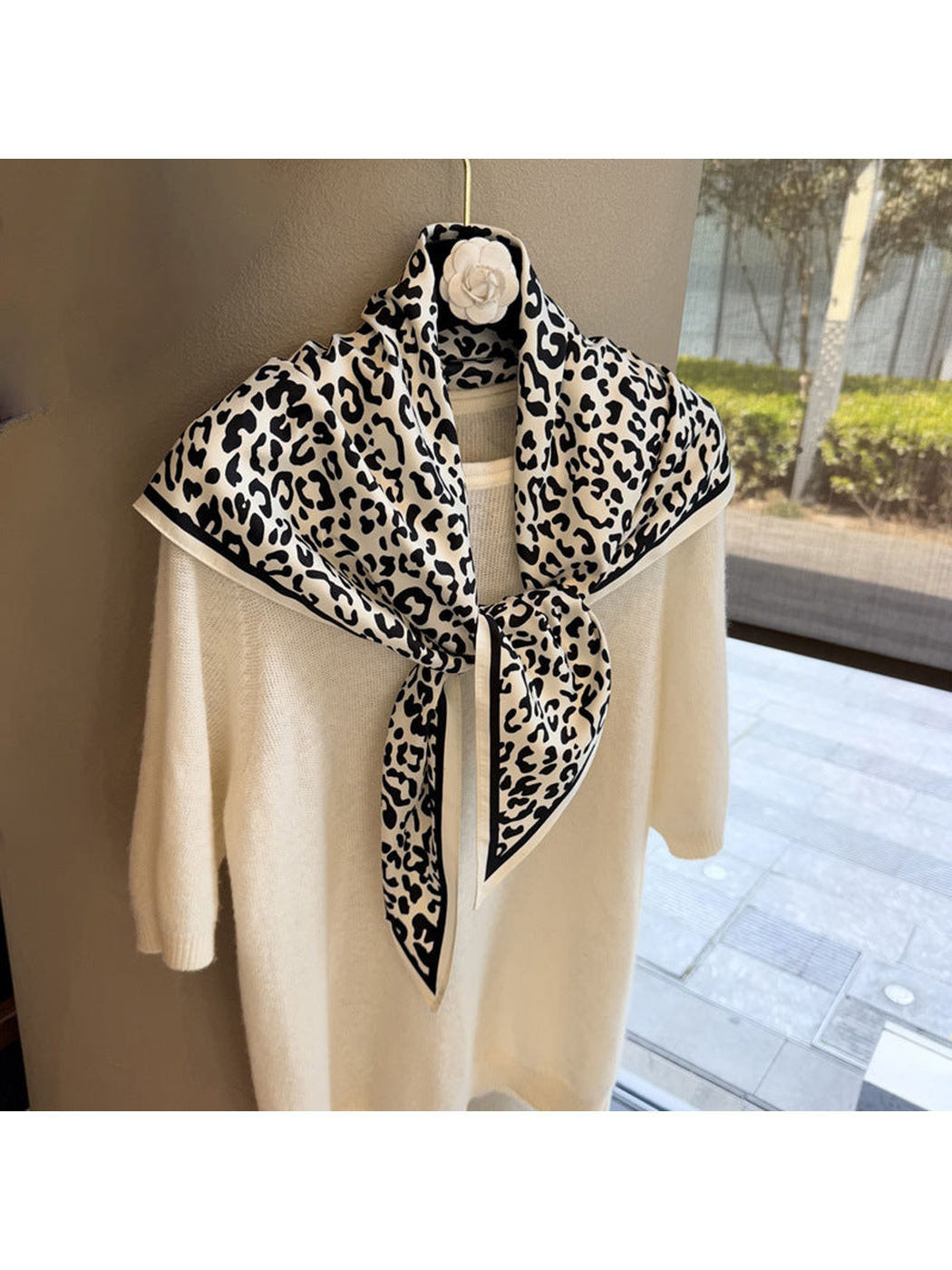 Ivory and black leopard-print triangle scarf tied over a cream sweater