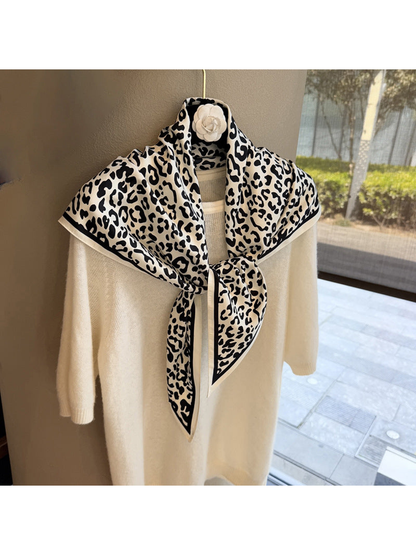 Ivory and black leopard-print triangle scarf tied over a cream sweater