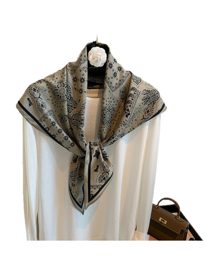 Gray paisley scarf tied over a white top, front view