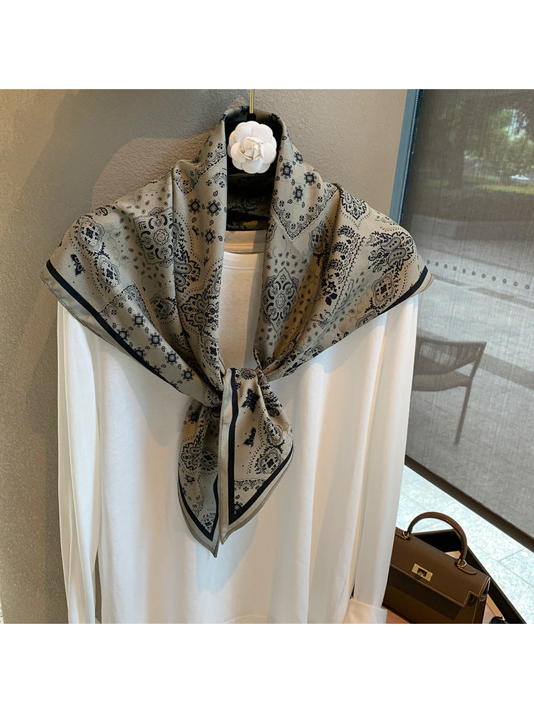 Gray paisley scarf tied over a white top