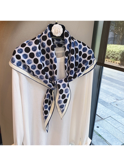 Blue polka-dot scarf tied over a white top