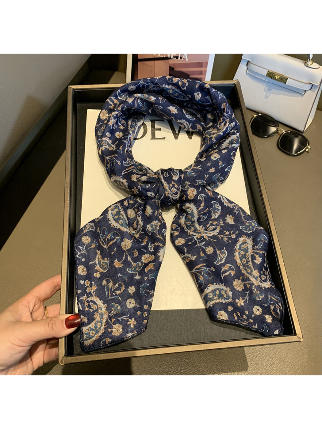 Navy paisley and floral scarf tied in a loop on a display tray