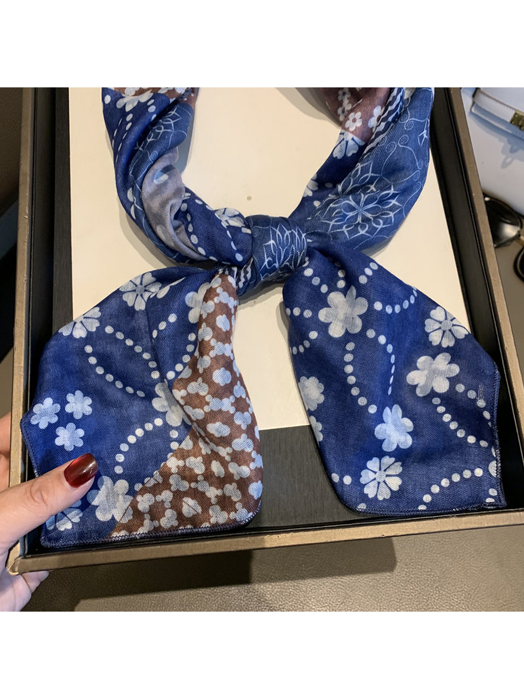Close-up of the scarf's floral patchwork print, fine woven-look texture and narrow stitched edge