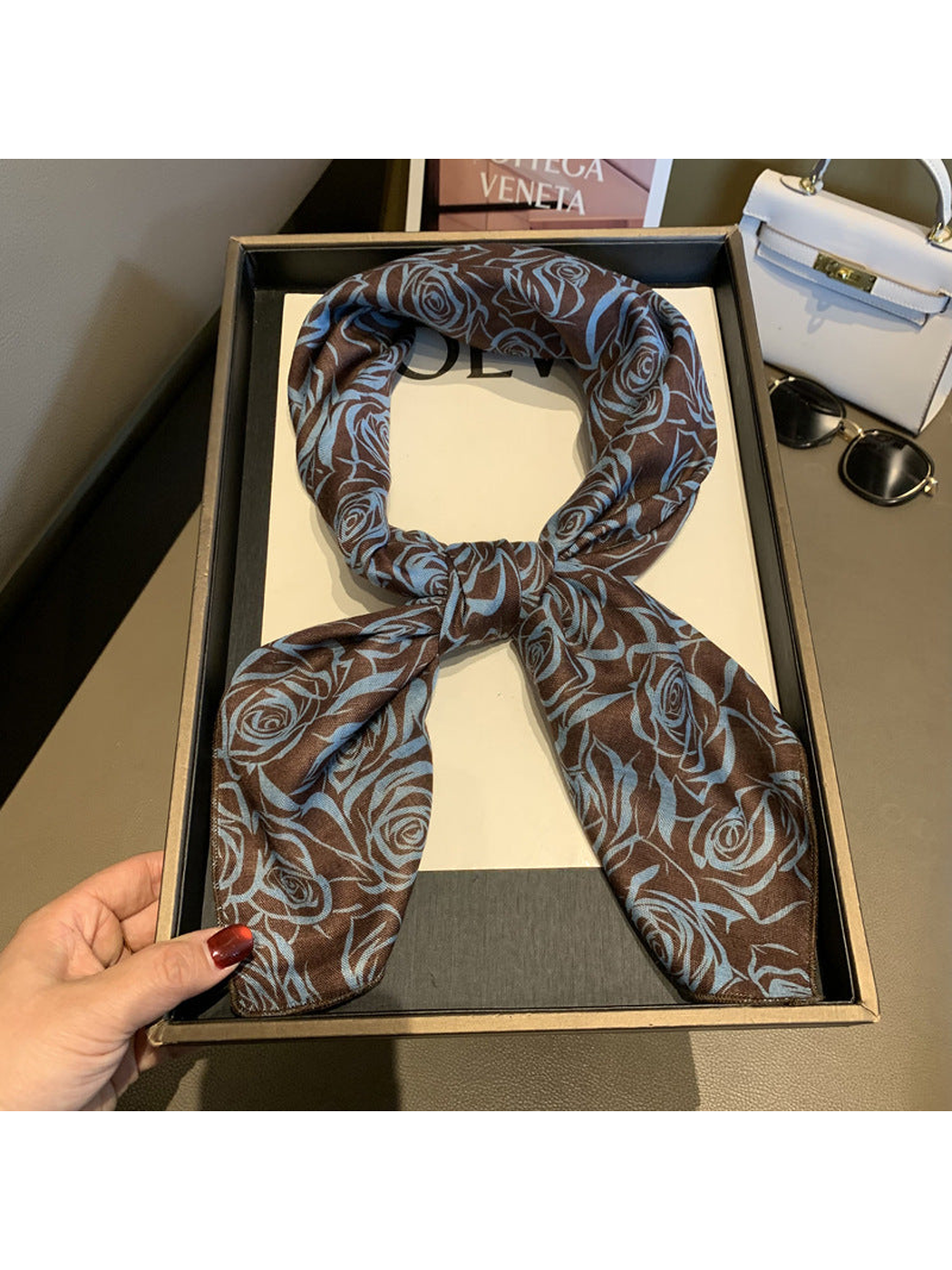 Brown square scarf with a light blue rose pattern, tied view