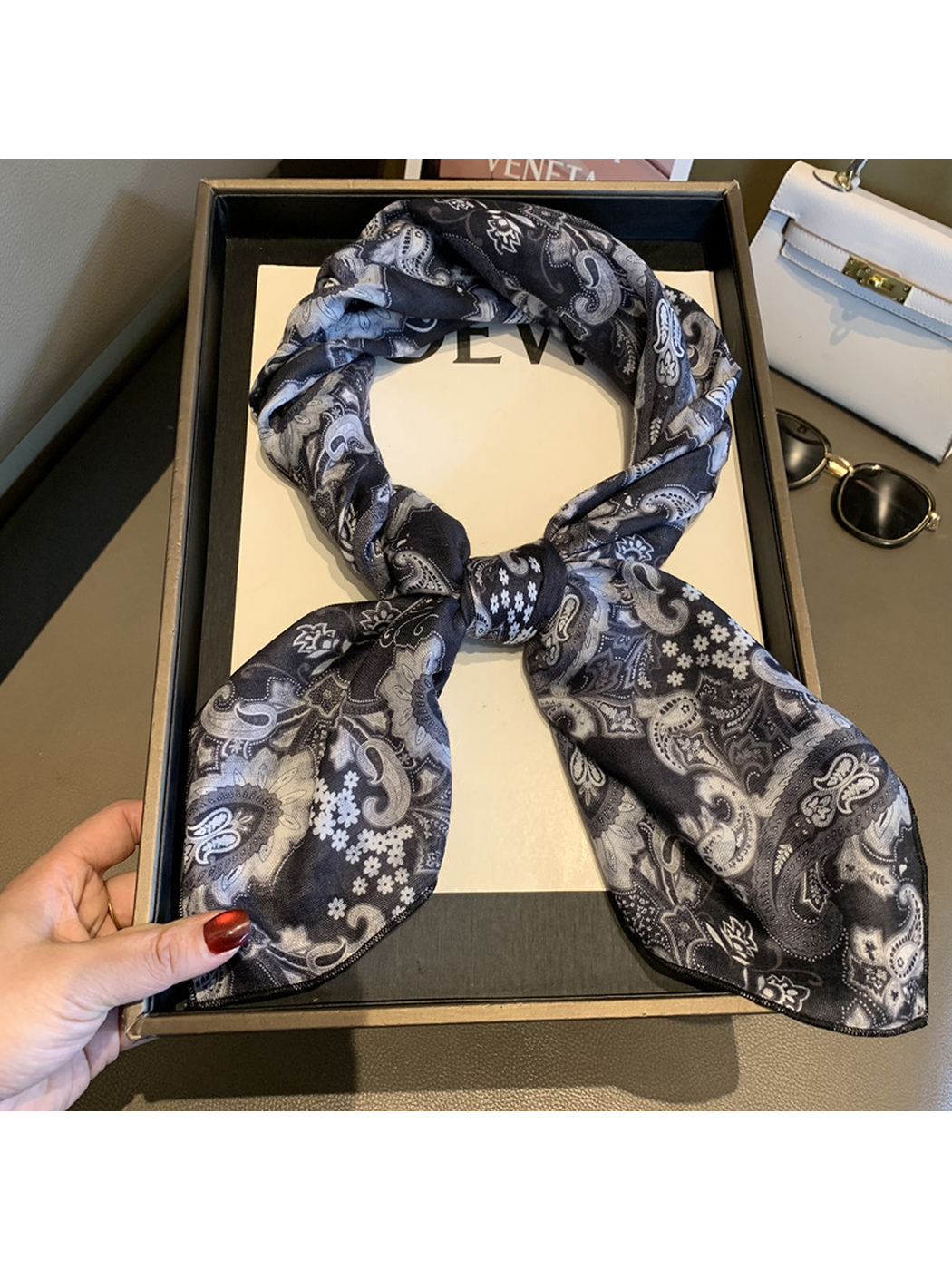Black and gray paisley square scarf tied in a looped knot