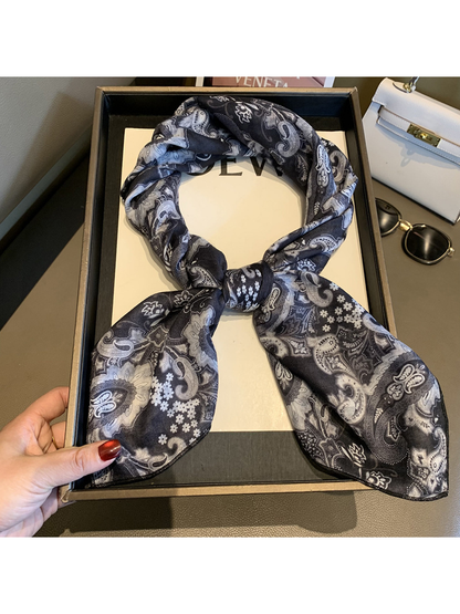 Black and gray paisley square scarf tied in a looped knot