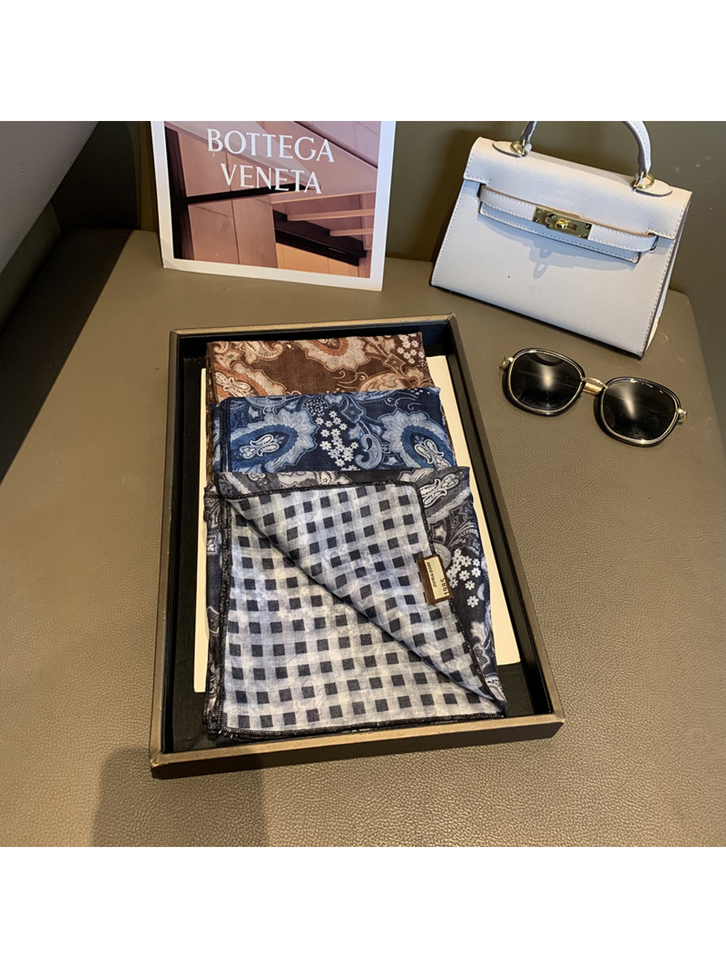 Folded paisley square scarves with a black and gray check reverse visible