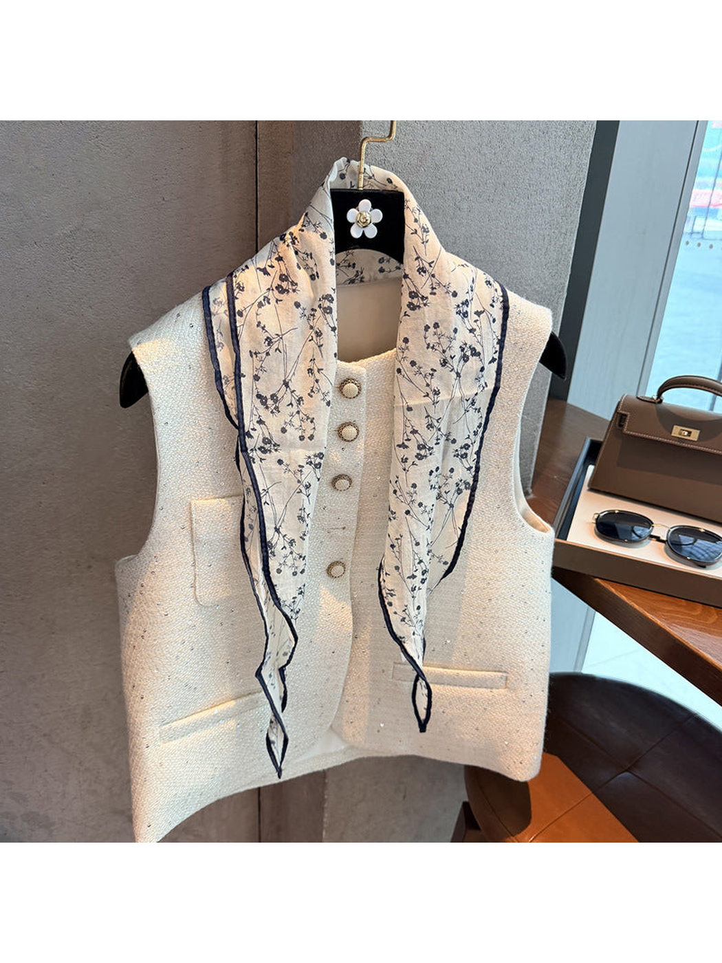 Navy floral triangle scarf draped loosely over a cream vest