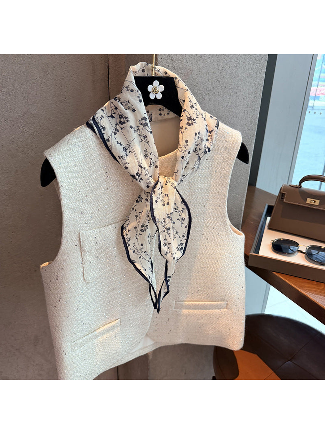 Navy floral triangle scarf tied at the neck over a cream vest