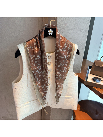 Brown floral triangle scarf draped over a cream vest