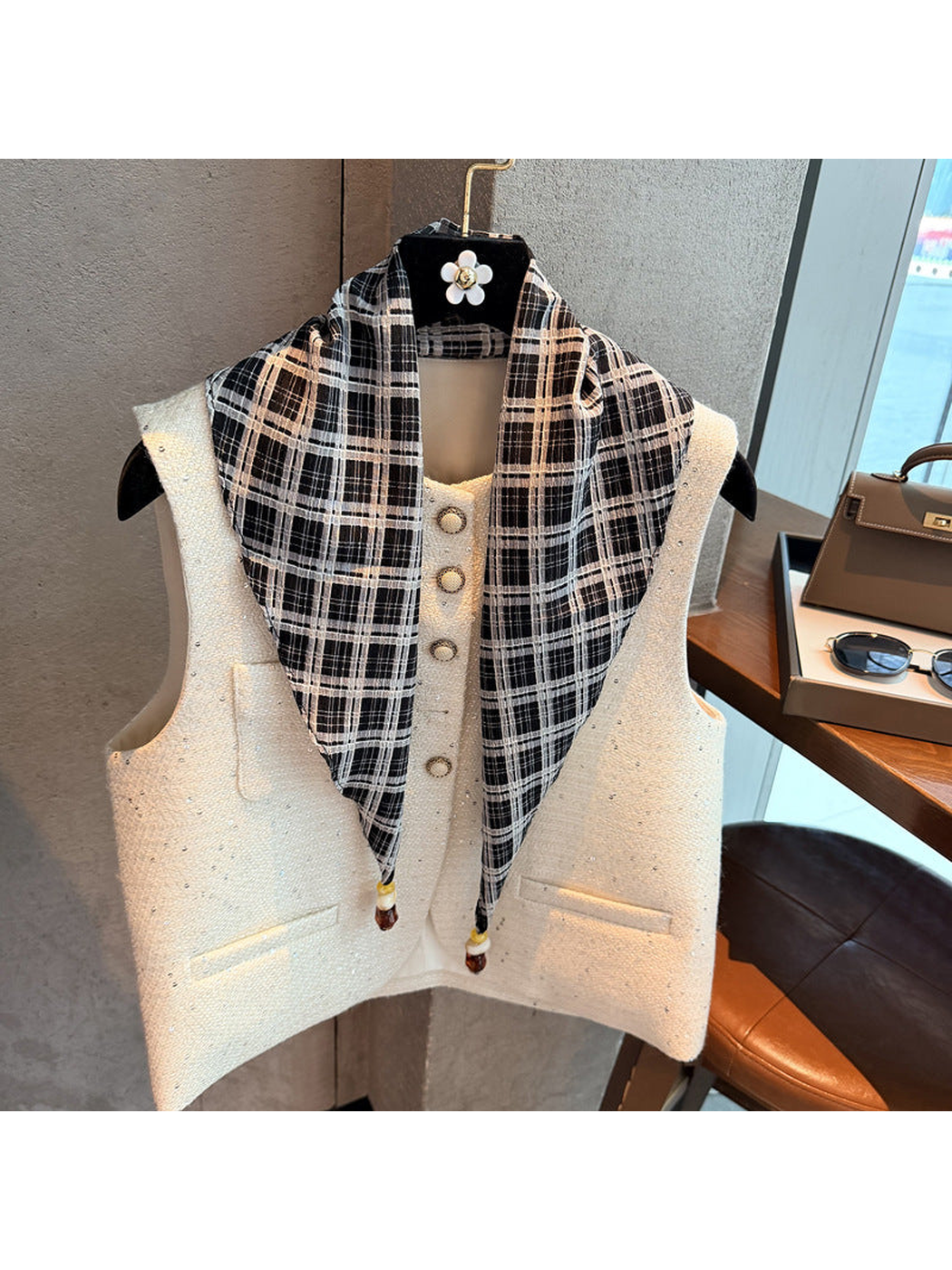 Black plaid scarf draped over a white vest with beaded pointed ends visible