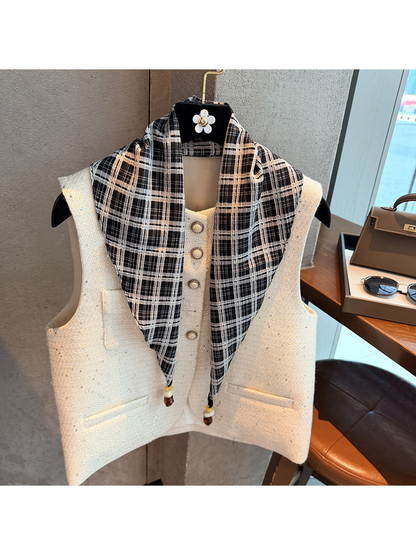 Black plaid scarf draped over a white vest with beaded pointed ends visible